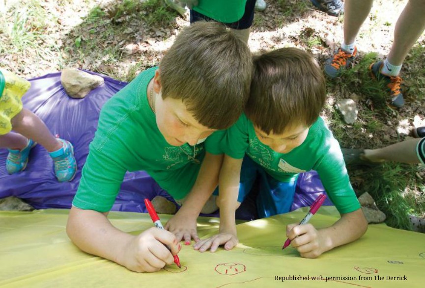 Two boys writing on a large poster image